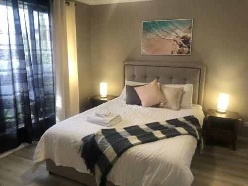 een slaapkamer met een groot bed en 2 lampen op tafels bij Sweet four bedroom home @cranbourne west in Cranbourne