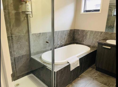 een badkamer met een bad en een wastafel bij Sweet four bedroom home @cranbourne west in Cranbourne