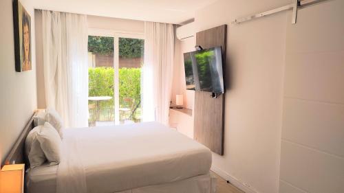 a bedroom with a bed and a tv and a window at Parador Búzios Boutique Hotel in Búzios