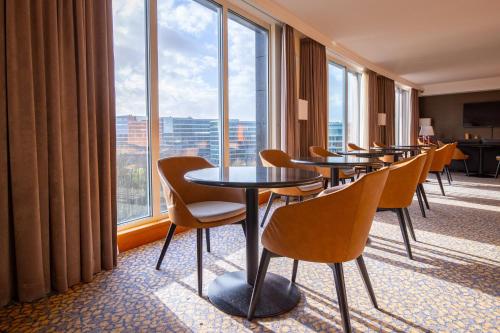 a row of tables and chairs in a room with windows at Crowne Plaza Brussels Airport by IHG in Zaventem