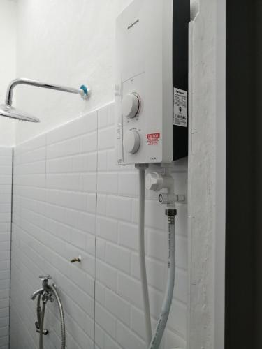 a shower in a bathroom with a white tiled wall at KJS Homestay, Layang-Layang, Johor in Kangkar Lanjut