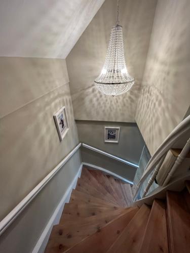 a staircase with a chandelier and a wooden floor at Chalet Embacher by AlpenTravel in Bad Gastein