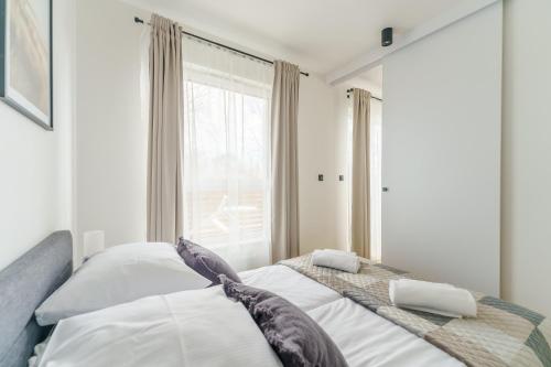 1 dormitorio con 2 camas y ventana en Apartament SEAGRASS SurfingBird Dźwirzyno en Dźwirzyno