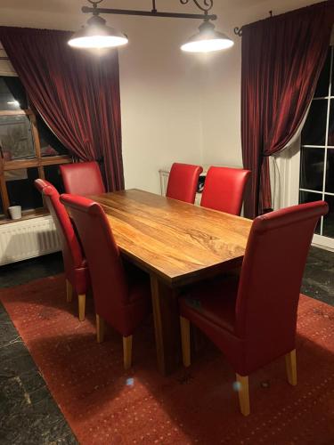 una mesa de madera con sillas rojas en una habitación en Ridge Wood House en Armagh
