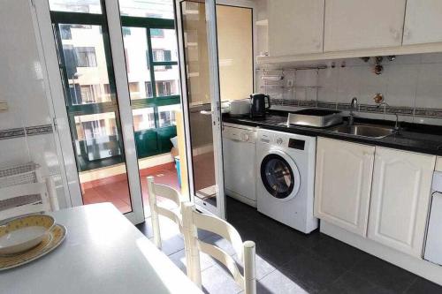 a kitchen with a washing machine and a table at SeaBreezeBonimar in Funchal