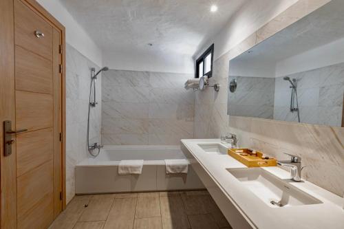 a bathroom with two sinks and a tub and a mirror at Hotel Kabila in M'diq