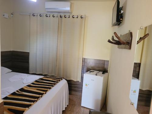 a bedroom with a bed and a television in a room at Pousada Betta in Pirenópolis