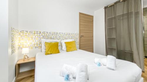 um quarto com uma grande cama branca com almofadas amarelas em HOMEY SNOW - Proche Gare - Balcon privé - Wifi em La Roche-sur-Foron