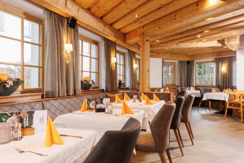 a restaurant with white tables and chairs and windows at Hotel Landgasthof Gappen in Kramsach