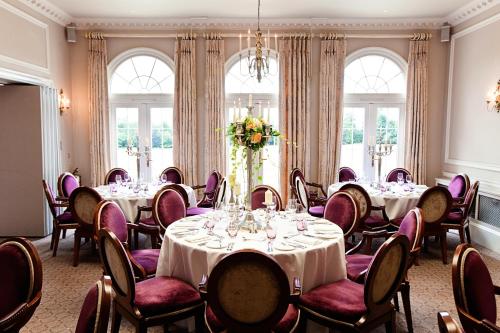 a conference room with tables and chairs and windows at Brockencote Hall in Kidderminster