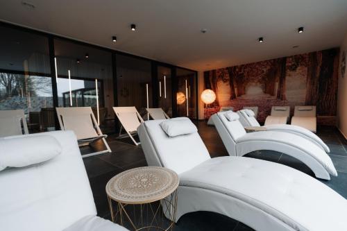 um quarto com cadeiras brancas, mesas e janelas em Domaine des Thermes em Awans