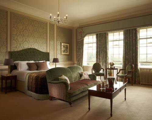 a bedroom with a bed and a couch and a chair at Brockencote Hall in Kidderminster