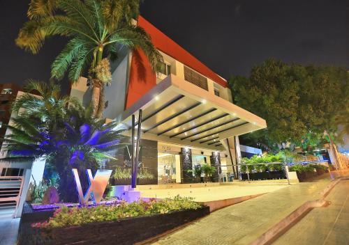 un edificio con palmeras delante de él por la noche en Washington Plaza en Barranquilla