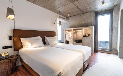 a bedroom with a large white bed and a large window at Hotel Cajú in Funchal