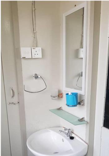 a white bathroom with a sink and a mirror at J & I Homestay 2 Person with shared bathroom in Sibu