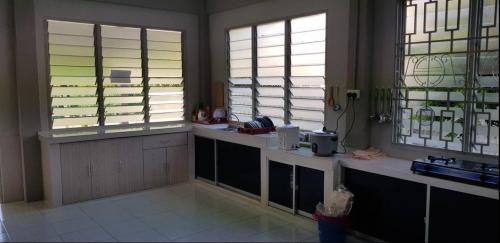 a kitchen with two windows and a counter with a sink at J & I Homestay 2 Person with shared bathroom in Sibu