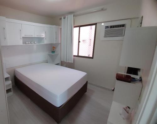 a white bedroom with a bed and a window at Apartamento com 2 quartos de FRENTE PARA O MAR in Maceió