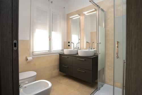 un bagno con due lavandini e una doccia in vetro di The White Building - [ROOMS] a Costermano