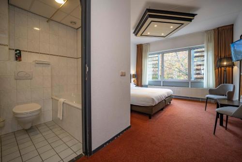 a hotel room with a bed and a bathroom with a tub at Fletcher Hotel Apeldoorn in Apeldoorn
