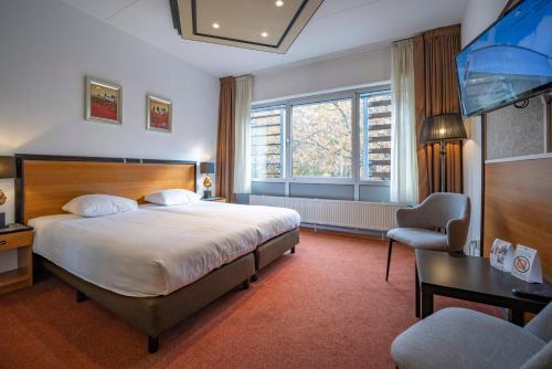 a bedroom with a bed and a desk and a television at Fletcher Hotel Apeldoorn in Apeldoorn