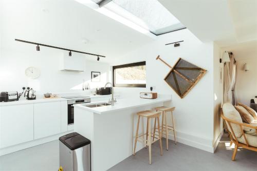 a kitchen with white counters and stools at The Hopper Huts in Faversham