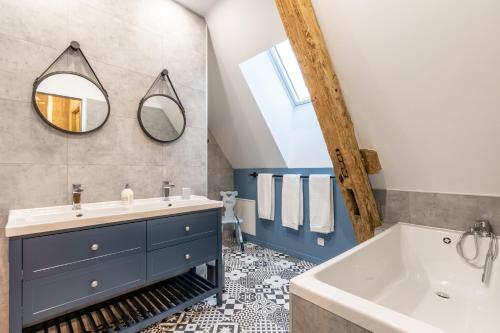 a bathroom with a sink and a tub and a mirror at Gite La Petite Ferme in Clermont-les-Fermes