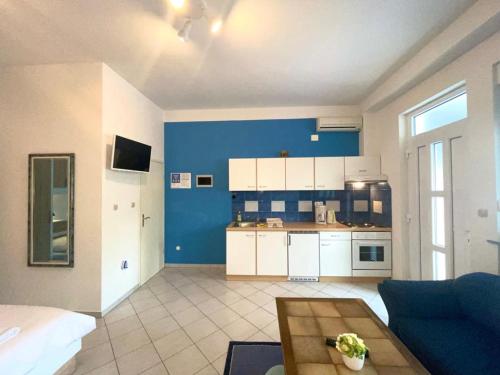 a living room with a blue and white kitchen at Apartmani Krajnović in Fažana