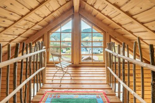 a staircase in a log cabin with a large window at Schwarzwald Blockhaus Flößerhaus - Kaminofen, Sauna in Schenkenzell