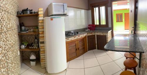 a kitchen with a refrigerator with a microwave on top at Pousada da Praia Imbé in Imbé