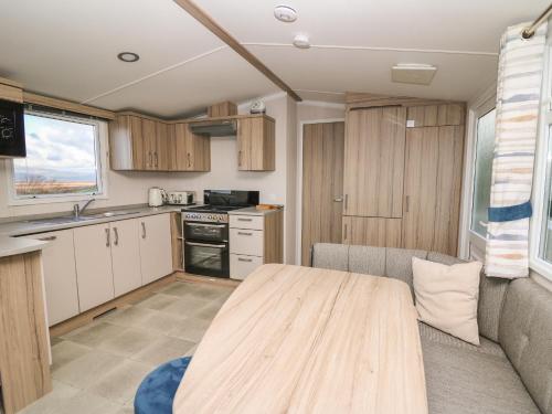 a kitchen with a wooden table in a caravan at Gwent 74 in Borth