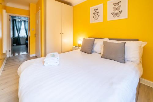 a bedroom with a large white bed with yellow walls at [COVENT GARDEN] Apartment in Central London in London