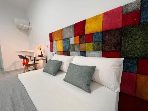 1 cama blanca con 2 almohadas y pared colorida en CH Barco, en Madrid