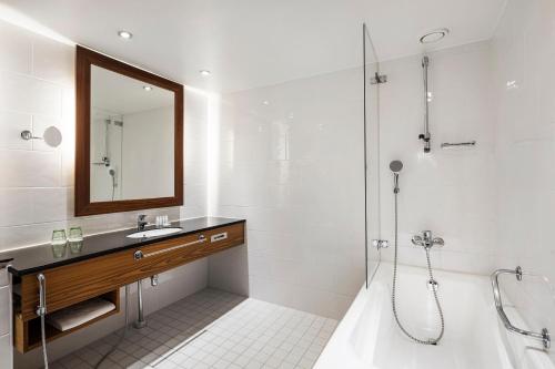 a bathroom with a shower and a sink and a mirror at Crowne Plaza Helsinki - Hesperia by IHG in Helsinki