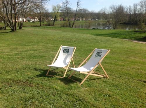 two lawn chairs sitting in the grass in a field at Le domaine de Marie in Port-sur-Saône