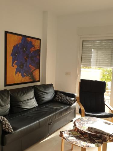 a living room with a black leather couch and a painting at VILLA DE SUABIA, Casa 9 in San Fulgencio