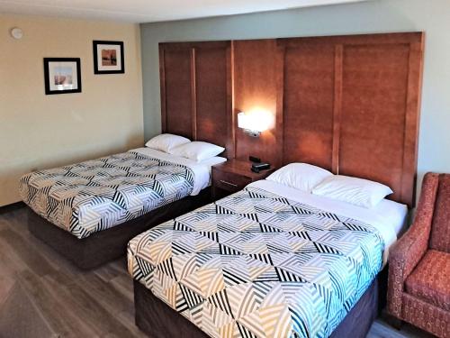 a hotel room with two beds and a chair at Suites Catonsville MD Baltimore West in Catonsville