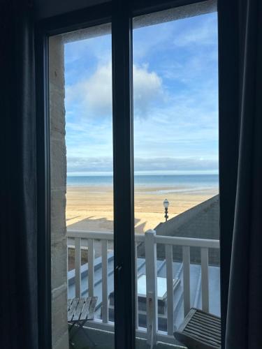 a room with a view of the beach from a window at Papagayo in Saint-Aubin-sur-Mer