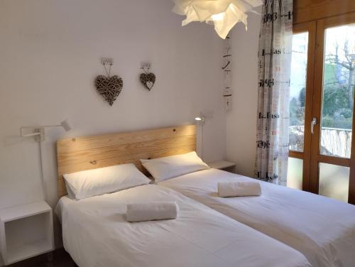 a bedroom with two beds with white sheets and a window at Casas Natura - Centro Graus in Graus