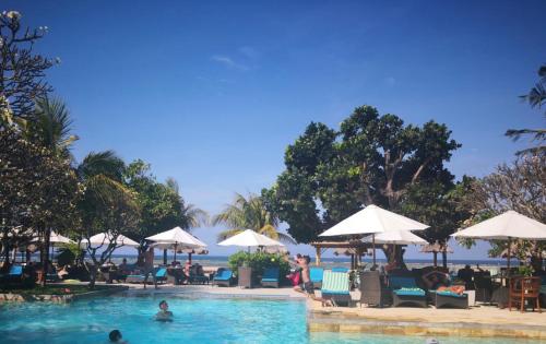 ein Pool in einem Resort mit Menschen im Wasser in der Unterkunft Peninsula Beach Resort in Nusa Dua