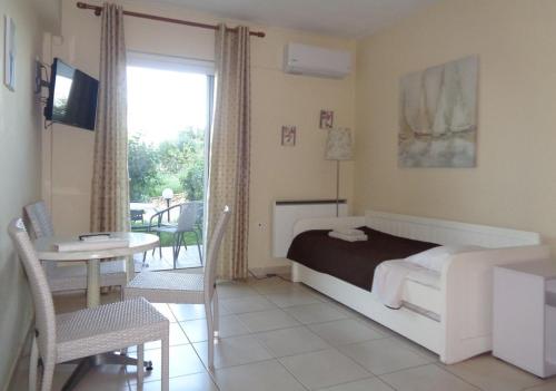 1 dormitorio con cama, mesa y balcón en Porto View Suites and Apartments, en Porto Heli
