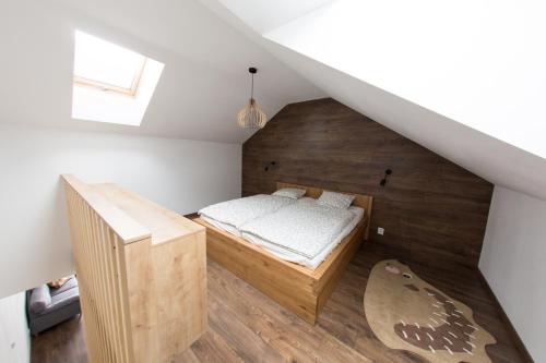 1 dormitorio con 1 cama y pared de madera en Apartman Cornus - Oravská Lesná, en Oravská Lesná