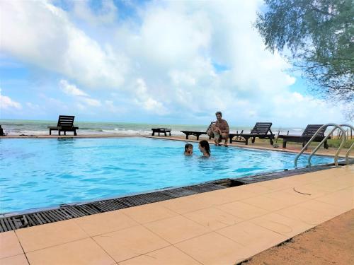 a man and a child in a swimming pool near the ocean at Hotel Coral Bay in Trincomalee