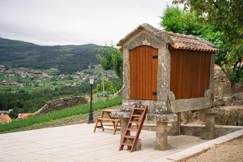 a small house with a wooden door and a ladder at Casa das Infusões - Soalheiro in Melgaço