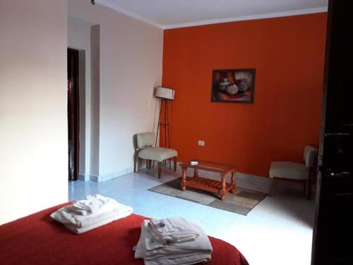 サルタにあるDel Sol 243のオレンジ色の壁のベッドルーム1室、ベッド1台、椅子が備わります。