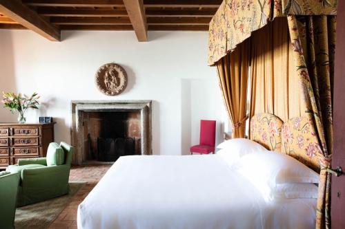 a bedroom with a large white bed and a chair at La Posta Vecchia Hotel in Ladispoli