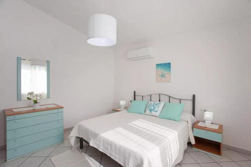 um quarto branco com uma cama e uma cómoda azul em Casa Salvo em Budoni