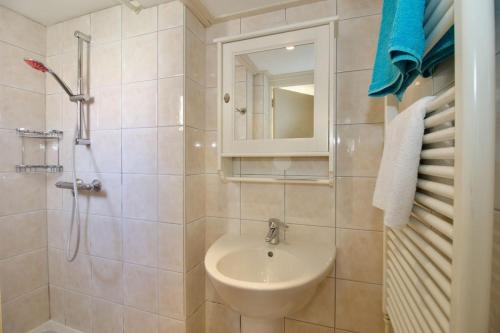 een badkamer met een wastafel en een douche met een spiegel bij Strand & Meer Domburg in Domburg