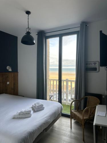 a bedroom with a bed and a view of the ocean at Papagayo in Saint-Aubin-sur-Mer