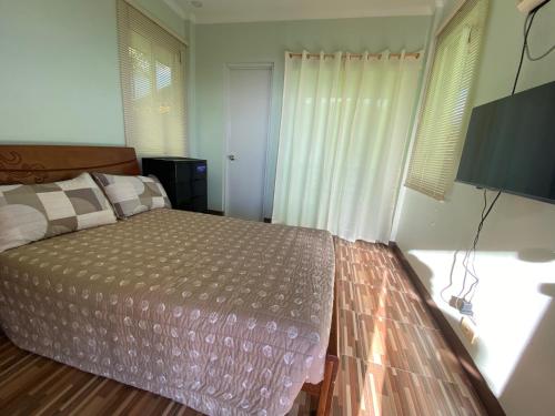 a bedroom with a bed and a large window at MS Mountain Cabin in Loboc