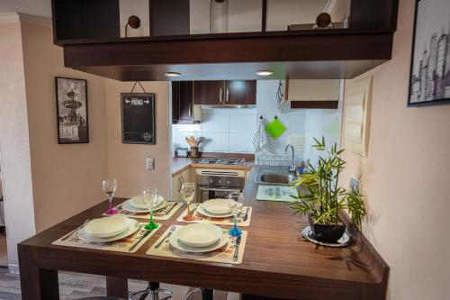 Una cocina con una mesa de madera con platos y copas de vino. en Departamento Temuco Centro, en Temuco